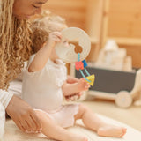 Child holding the PlanToys first shape sorter wooden baby toy with the wooden shapes hanging on the attached rope.