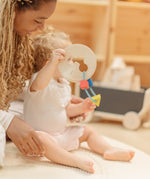 Child holding the PlanToys first shape sorter wooden baby toy with the wooden shapes hanging on the attached rope.