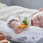 Close up of a sleeping baby holding onto the PlanToys plastic-free wooden flexi jellyfish toy