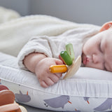 Close up of a sleeping baby holding onto the PlanToys plastic-free wooden flexi jellyfish toy