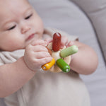 Close up of a baby's hand  holding the PlanToys flexi jellyfish baby teething toy. 