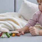 Young girl laying on a grey floor pressing down the top of the PlanToys flexi jellyfish with her finger