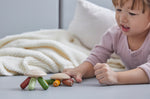 Young girl laying on a grey floor pressing down the top of the PlanToys flexi jellyfish with her finger