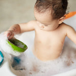 A child in a tub full of bubbly water playing with the PlanToys Fountain Bowl Set. 