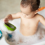 A child in a tub full of bubbly water playing with the PlanToys Fountain Bowl Set. 