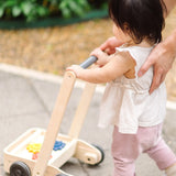 Child pushing the PlanToys gear & go push along wooden baby walker. 