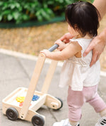 Child pushing the PlanToys gear & go push along wooden baby walker. 
