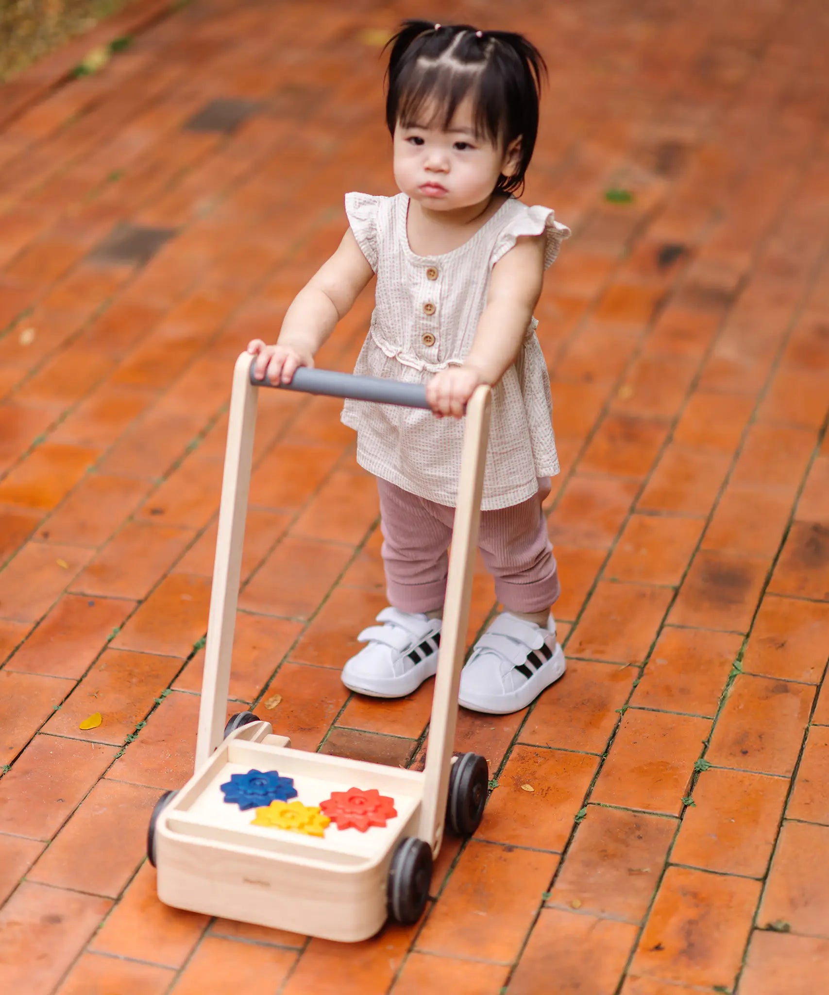 Child pushing the PlanToys gear & go push along wooden baby walker. 