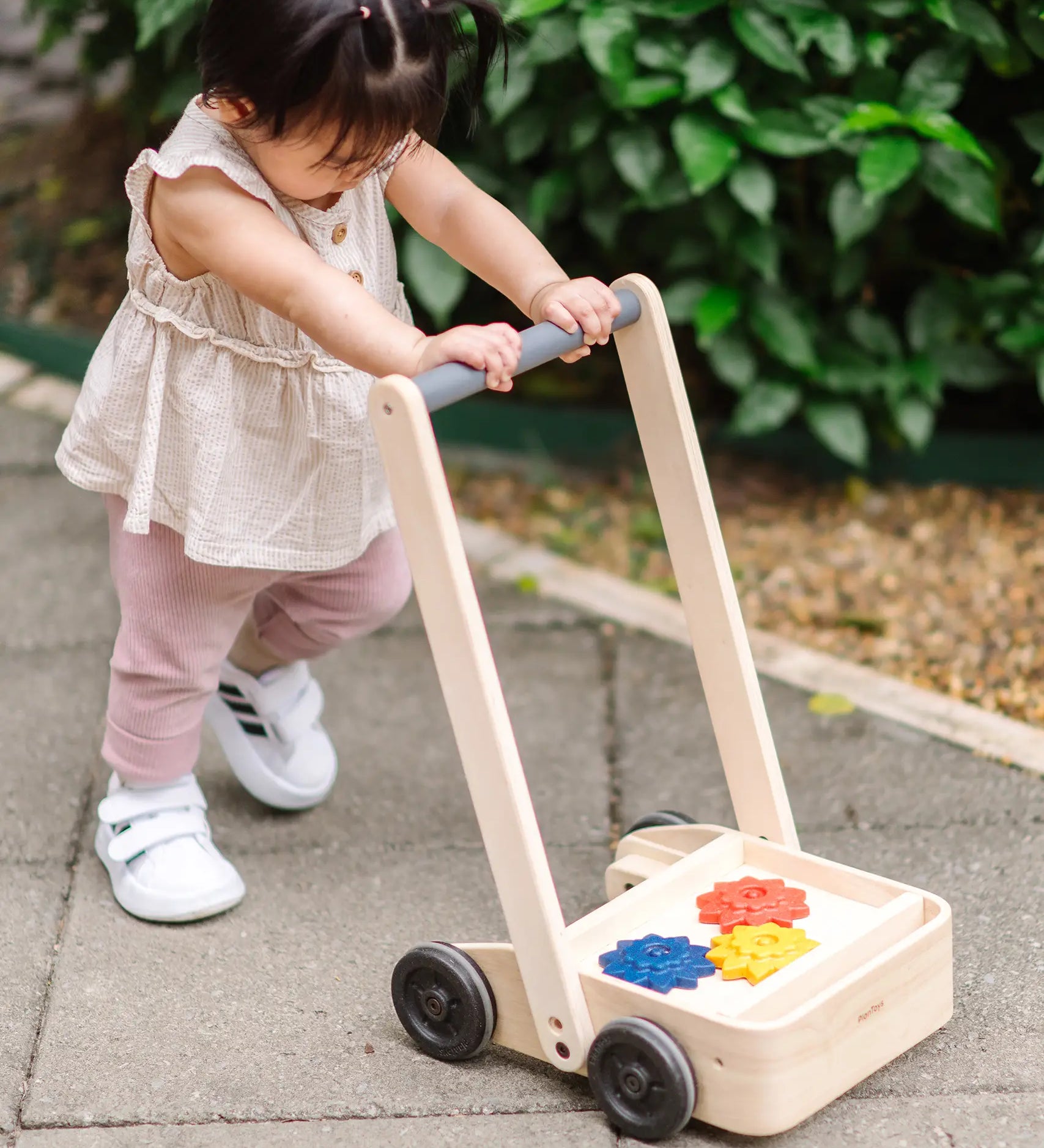 Child pushing the PlanToys gear & go push along wooden baby walker. 