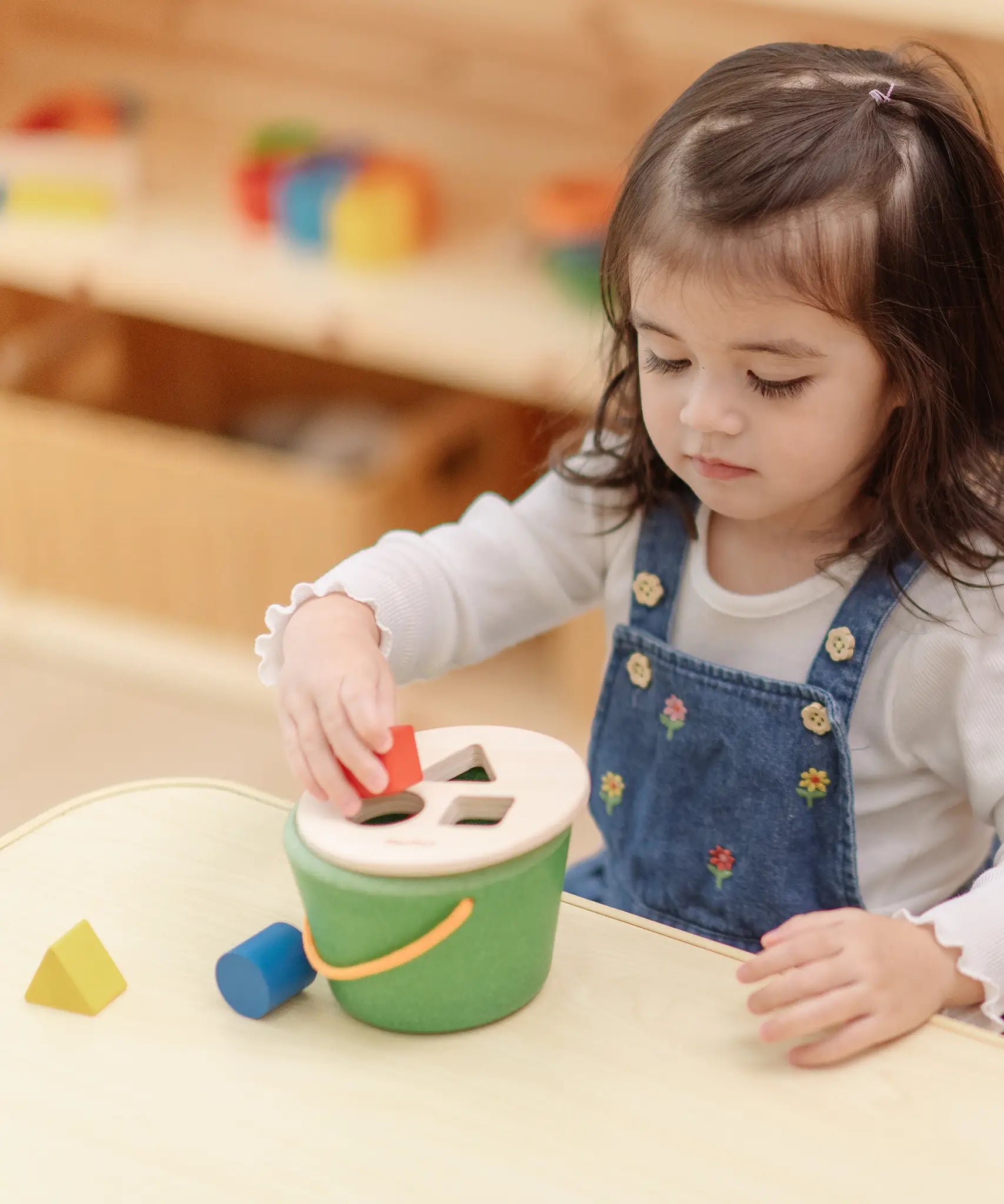 Child playing with the PlanToys geo sorting bucket wooden shape sorting toy. 
