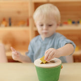 Child placing the yellow cube into the PlanToys geo sorting bucket wooden shape sorting toy. 