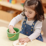 Child taking the wooden blocks out of the PlanToys geo sorting bucket wooden shape sorting toy. 