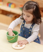 Child taking the wooden blocks out of the PlanToys geo sorting bucket wooden shape sorting toy. 