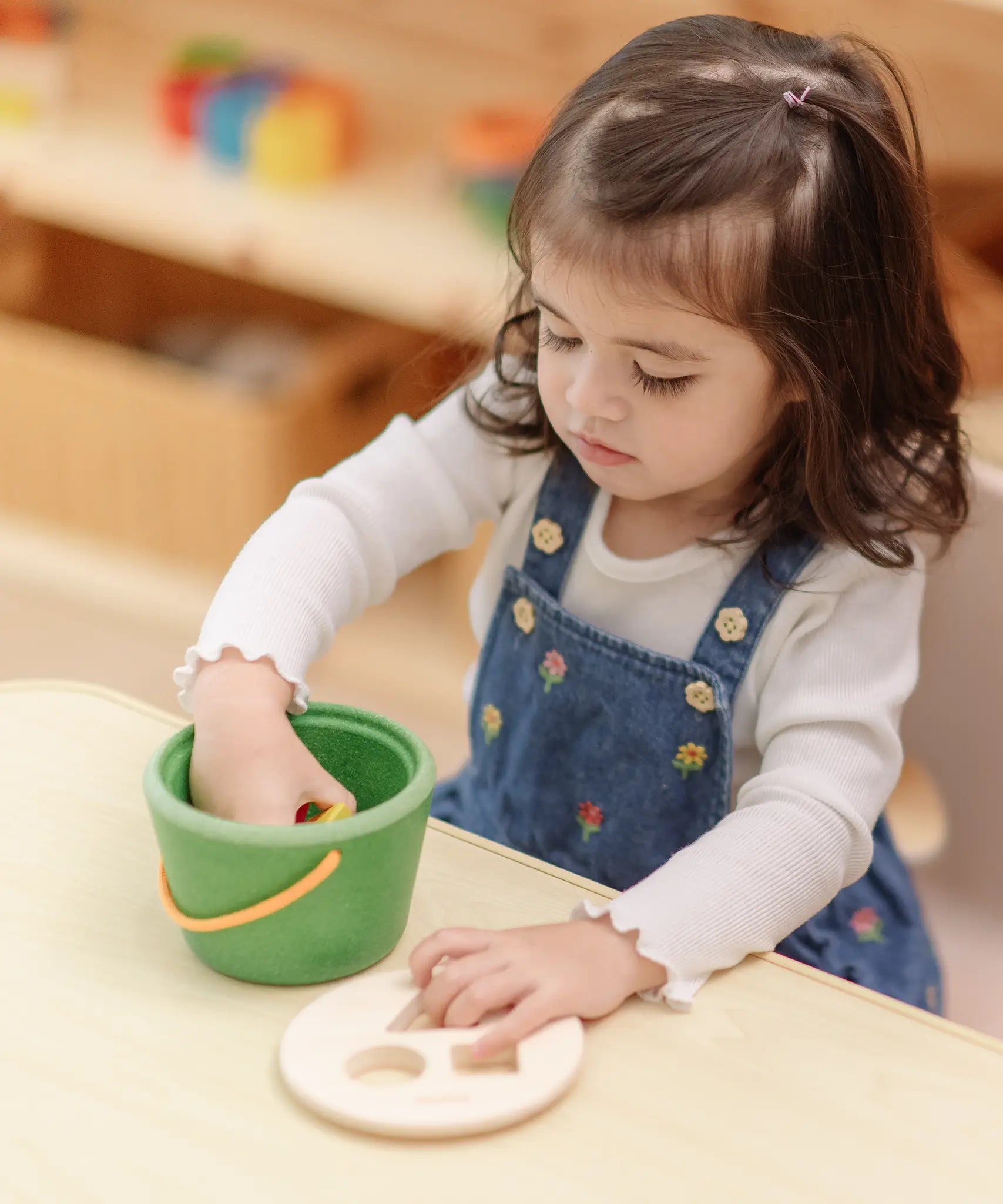Child taking the wooden blocks out of the PlanToys geo sorting bucket wooden shape sorting toy. 
