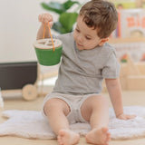 Child holding the PlanToys geo sorting bucket wooden shape sorting toy in their hand. 