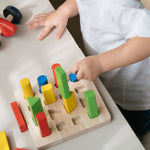 A child playing with the PlanToys Geometric Peg Board.