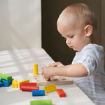 A child playing with the PlanToys Geometric Peg Board.
