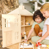 Children playing with the PlanToys wooden Georgian dollhouse children's toy. The house has been filled with dolls house furniture.