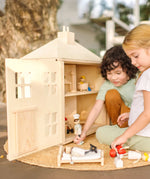 Children playing with the PlanToys wooden Georgian dollhouse children's toy. The house has been filled with dolls house furniture.