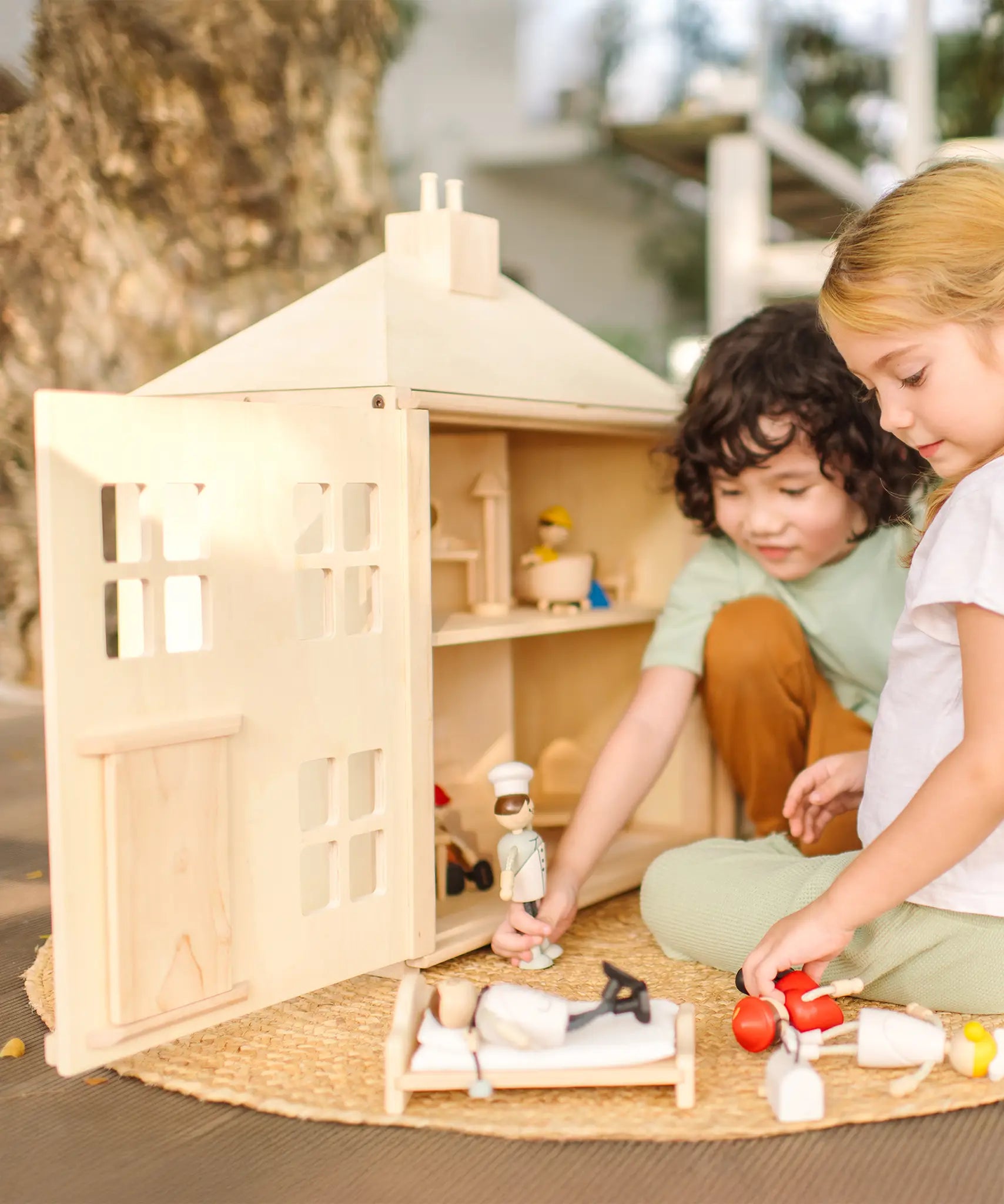 Children playing with the PlanToys wooden Georgian dollhouse children's toy. The house has been filled with dolls house furniture.
