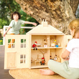 Children playing with the PlanToys wooden Georgian dollhouse children's toy. The house has been filled with dolls house furniture.