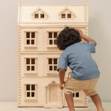 Child looking through the window of the PlanToys Grand Victorian Dollhouse. 
