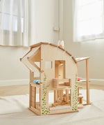 The PlanToys Green Dolls' House and Furniture Set placed on a white rug in the middle of a room.