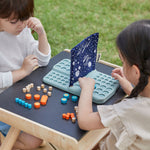 Two children sitting at opposite side of the PlanToys desk playing with the PlanToys Guess My Planet Game.
