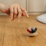 A hand shown spinning the PlanToys Flexi Jellyfish wooden high contrast baby toy. A wooden top with high contrast, white, greys, black and red flexible wooden pieces for the jellyfish legs. PlanToys range of toys are made from sustainably sourced rubberwood, we're proud stockists of PlanToys here at Babipur. 