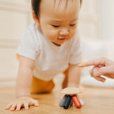 A baby crawling towards the PlanToys Flexi Jellyfish wooden high contrast baby toy. A wooden top with high contrast, white, greys, black and red flexible wooden pieces for the jellyfish legs. PlanToys range of toys are made from sustainably sourced rubberwood, we're proud stockists of PlanToys here at Babipur. 