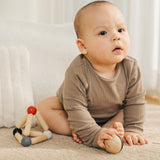 A baby holding the ball that comes inside the PlanToys high contrast Triangle baby Clutching Toy. A black and natural wood wooden ball in a stretchy triangle clutching toy. PlanToys range of toys are made from sustainably sourced rubberwood, we're proud stockists of PlanToys here at Babipur. 