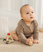 A baby holding the ball that comes inside the PlanToys high contrast Triangle baby Clutching Toy. A black and natural wood wooden ball in a stretchy triangle clutching toy. PlanToys range of toys are made from sustainably sourced rubberwood, we're proud stockists of PlanToys here at Babipur. 