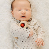 A baby with a PlanToys Shaking Rattle in a High Contrast colourway under their arm. The red and black details stand out against the natural rubberwood body. PlanToys range of toys are made from sustainably sourced rubberwood, we're proud stockists of PlanToys here at Babipur. 