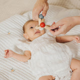 An adult holding the PlanToys high contrast square clutching toy above a baby. PlanToys range of toys are made from sustainably sourced rubberwood, we're proud stockists of PlanToys here at Babipur. 