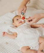 An adult holding the PlanToys high contrast square clutching toy above a baby. PlanToys range of toys are made from sustainably sourced rubberwood, we're proud stockists of PlanToys here at Babipur. 