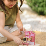 Child playing with the PlanToys ice cream shop wooden toy playset placing the ice creams on a stand at the front of the shop.
