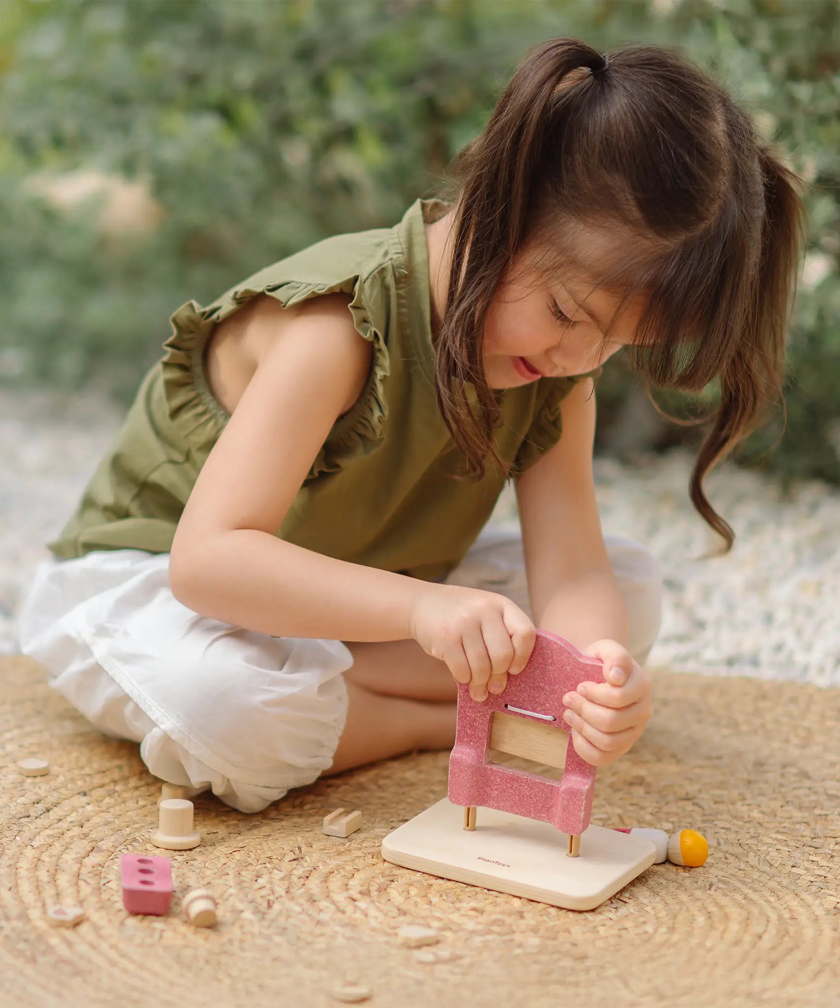Child assembling the PlanToys ice cream shop wooden toy playset.