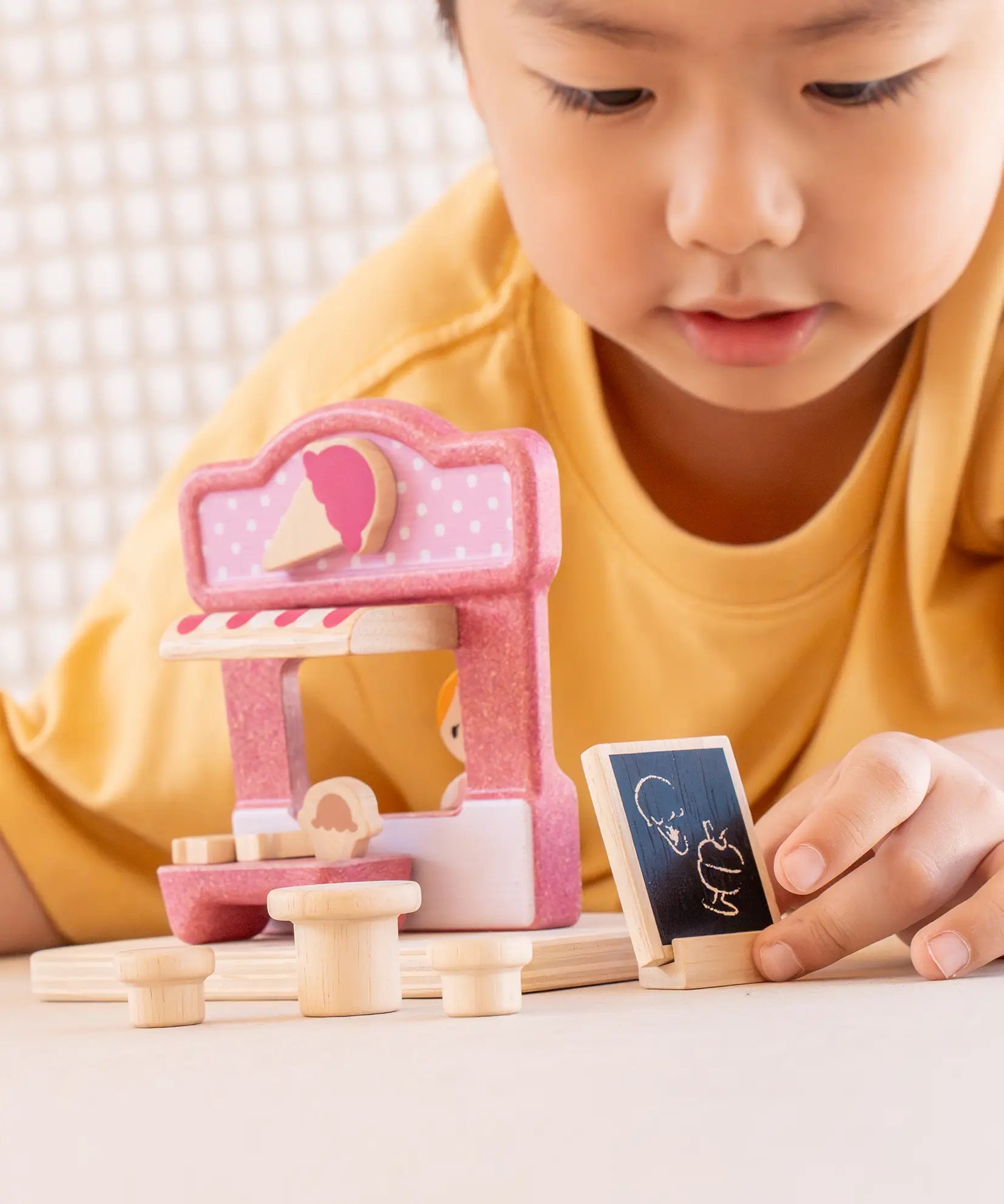 Child playing with the PlanToys ice cream shop wooden toy playset.
