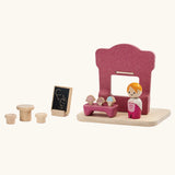Back of the PlanToys ice cream shop wooden toy playset. Pink wooden shop with three ice cream cones, advert board, table and two seats and a worker figure.