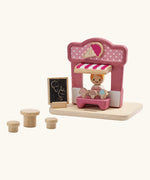 PlanToys ice cream shop wooden toy playset. Pink wooden shop with three ice cream cones, advert board, table and two seats and a worker figure.