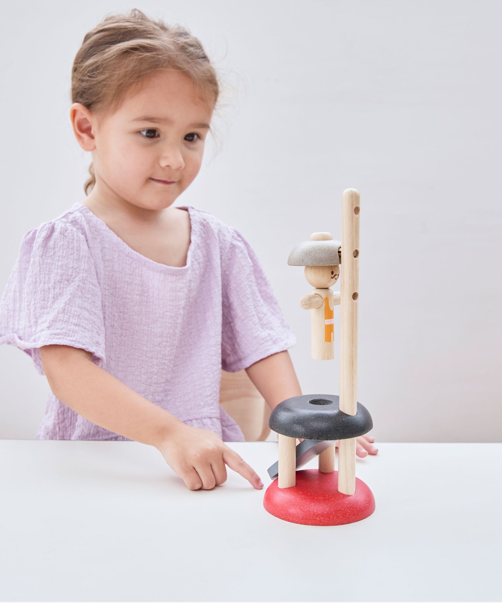 A child playing with the PlanToys Natural Rubberwood Jumping Acrobat Toy. PlanToys have a vast range of sustainable wooden toys are available at Babipur.