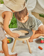 Close up of two children crouched around the PlanToys BBQ toy