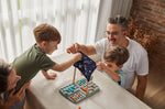 A family sitting around a table playing the PlanToys Guess My Planet Game. 
