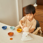 Young boy putting a PlanToys wooden Waldorf cup into its drawstring bag