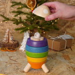 Close up of hand holding a piece of the PlanToys wooden stacking rocket toy above the astronaut