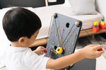 Close up of a child pulling the strings on the PlanToys wall ball game to make the ball move up the board.