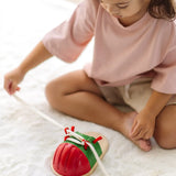Child tying the laces on the PlanToys life size tie-up wooden shoe toy. 