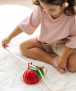Child tying the laces on the PlanToys life size tie-up wooden shoe toy. 