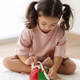 Child tying the laces on the PlanToys life size tie-up wooden shoe toy. 