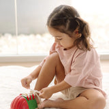 Child tying the laces on the PlanToys life size tie-up wooden shoe toy. 